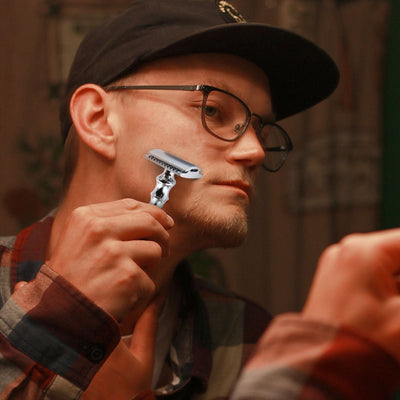 Man shaving with the silver Bleoberis Closed Comb Safety Razor