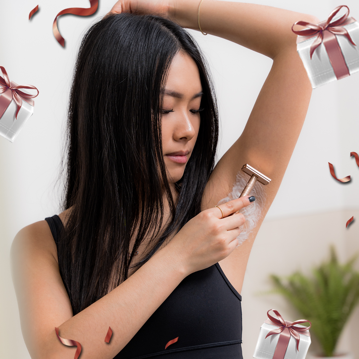 A woman using a the Henson AL13 Safety Razor Copper to shave her underarm surrounded by Mother's Day themed gift boxes and confetti.